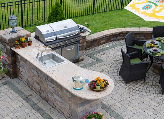 Outdoor kitchen and grill area beside a pool